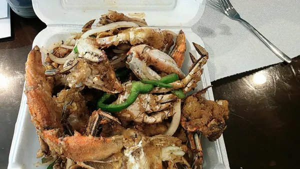 A takeout box of crabs tossed with green peppers and onions