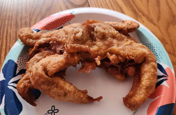 Two battered fried crabs on a paper plate