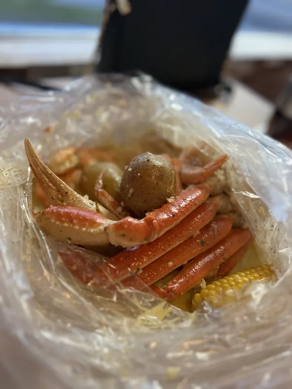 Snow crab legs, a potato and corn in a seasoned boil bag