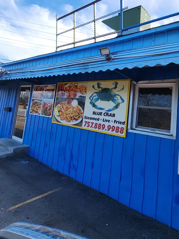 A sign on the blue wall of Ocean Blue with a blue crab and the words Blue Crab, Steamed, Live, Fried, 757.889.9988